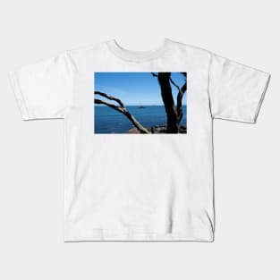 View through twisted pohutukawa tree branches across barge with crane blue ocean to distant horizon Kids T-Shirt